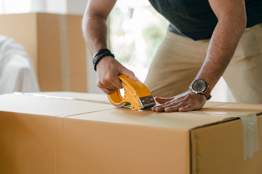 pexels-photo-4246124 Crop unrecognizable young male in casual clothes packing cardboard box and sealing with scotch tape